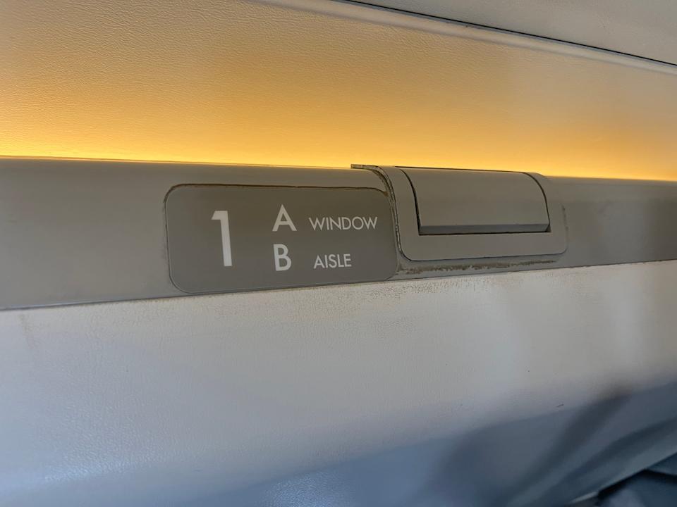 A close-up of seat numbers 1A and 1B on a plane.