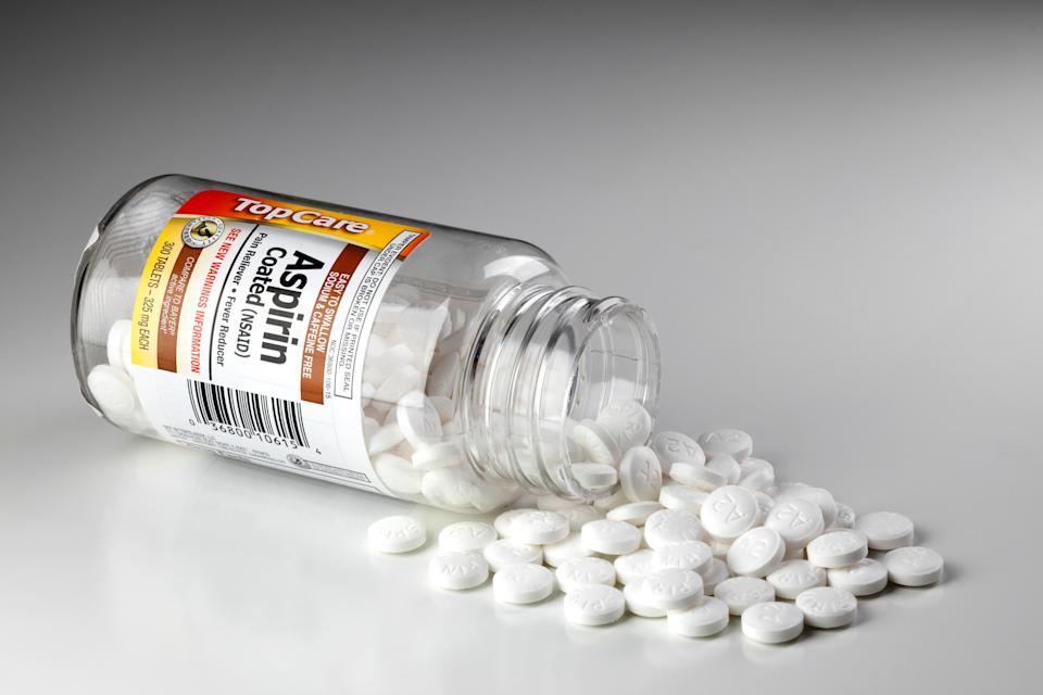 Spilled aspirin pills from a labeled bottle on a smooth surface