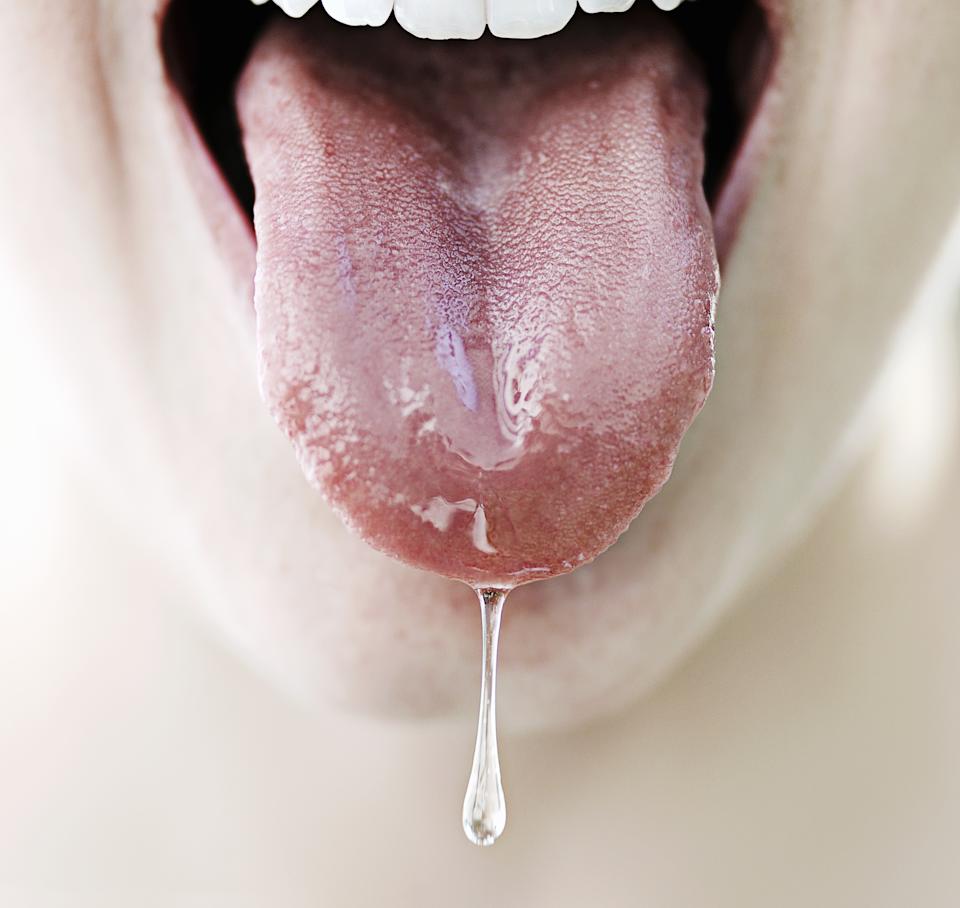 Close-up of a person sticking out their tongue with saliva dripping from its tip