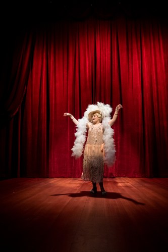 an actress in a boa poses in a hat