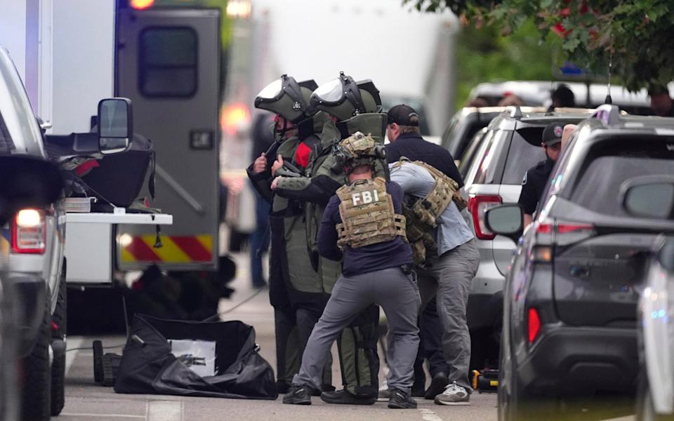 Law enforcement officials in protective gear investigate after the attack