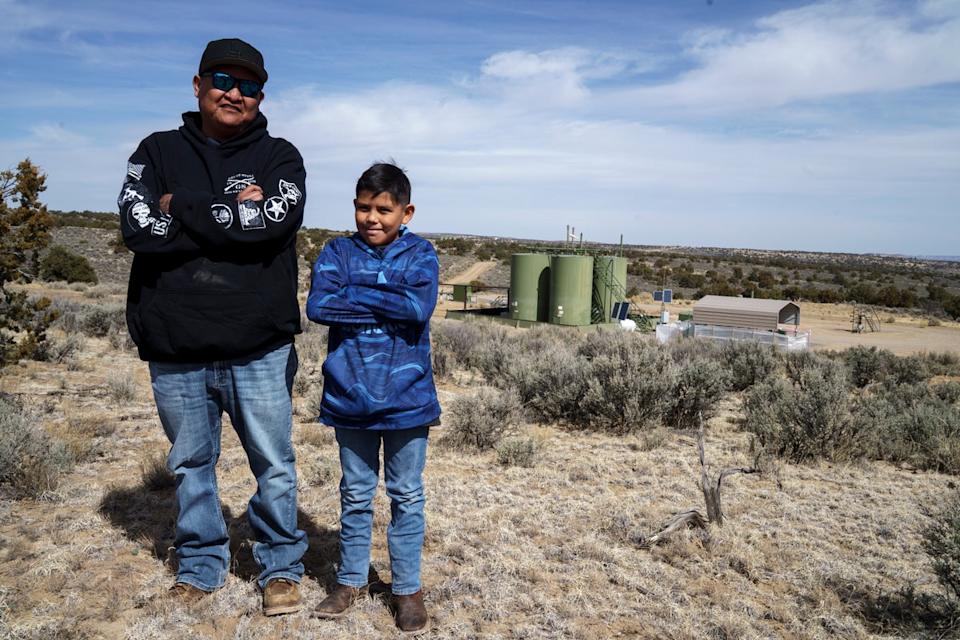 Billton Werito and his son Amari stand in front of a drilling pad near their house in an area where oil and gas drilling close to a local elementary school is causing students, including Amari, to miss school from negative health effects according to Werito, in Counselor, N.M., Navajo Nation (Searchlight New Mexico)