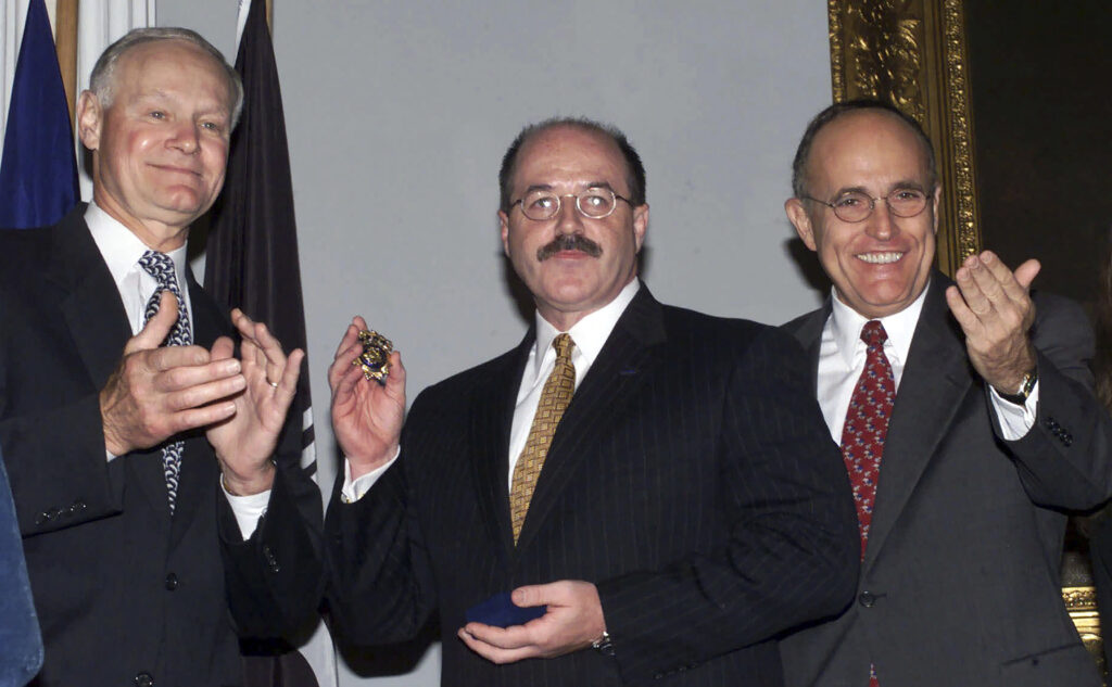 FILE— Former Police Commissioner Howard Safir, left, presents the official police commissioner's badge to the newly named New York City police commissioner, Bernard Kerik, center, as Mayor Rudolph Giuliani looks on, at New York's City Hall, Aug. 19, 2000.
