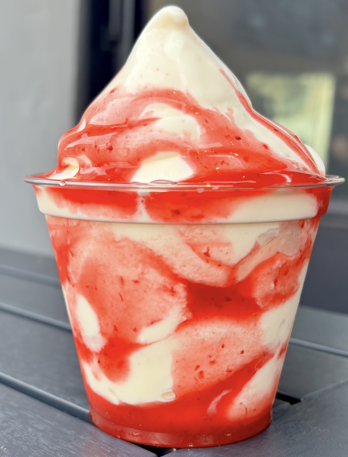 A plastic cup filled with frozen vanilla custard with strawberry sauce from NFA Burger